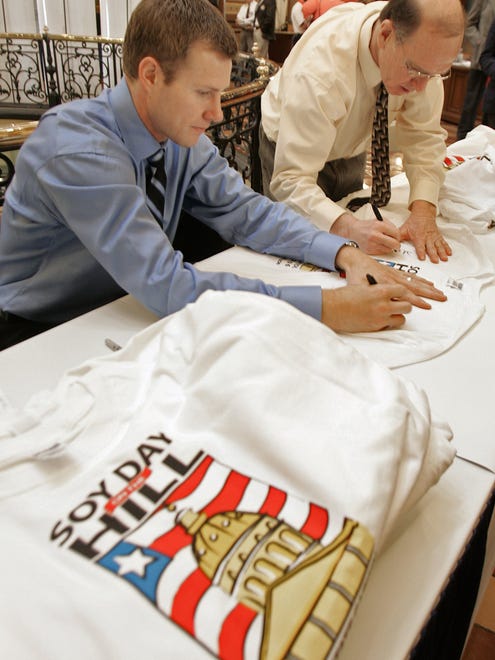 In this March 7, 2006 photo, Fred Hoiberg, left, former Iowa State University basketball star and guard with the NBA Timberwolves, and Dan Gable, former University of Iowa wrestling coach, autograph shirts Tuesday at the Iowa Statehouse as part of Soy Day activities.