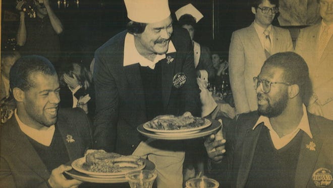 Mel Cole, left, and Andre Tippett are served dinner by Hayden Fry on Dec. 25, 1981 before the 1982 Rose Bowl game.