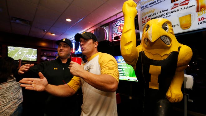 Troy Vanni of Clive (left), Daryl Blanshan of Des Moines and Herky the Hawk watch Iowa players drive down the field against Michigan State in the Big 10 championship Saturday Dec. 5, 2015, at The Front Row bar in Clive.