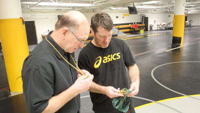 Former Hawkeye wrestling coach Dan Gable, left, and current head coach Tom Brands compare their Olympic gold medals at the Dan Gable Wrestling Complex in Carver-Hawkeye Arena on Friday, April 13, 2012. Gable wears his 1972 Olympic gold medal while Brands sports his won in the 1996 Games.