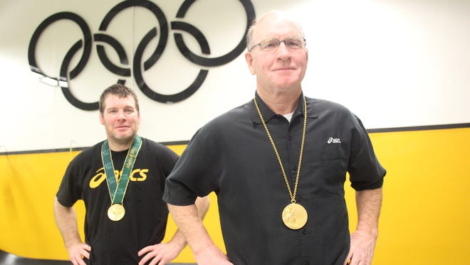 Former Hawkeye wrestling coach Dan Gable, right, and current head coach Tom Brands are photographed at the Dan Gable Wrestling Complex in Carver-Hawkeye Arena on Friday, April 13, 2012. Gable wears his 1972 Olympic gold medal while Brands sports his won in the 1996 Games.