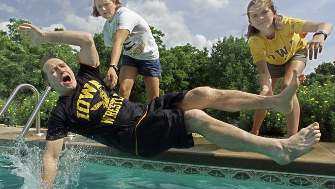 In this June 18, 2002 photo, Dan Gable gets dumped in his backyard pool by daughters Molly, 19, left and Mackenzie, 14.