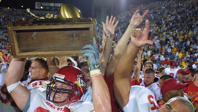 Iowa State's Kyle Knock (93) holds the Cy-Hawk trophy up in celebration of the Cyclones' 36-31 win against Iowa on Sept. 14, 2002 at Kinnick Stadium in Iowa City. Beau Coleman (55) is also pictured.