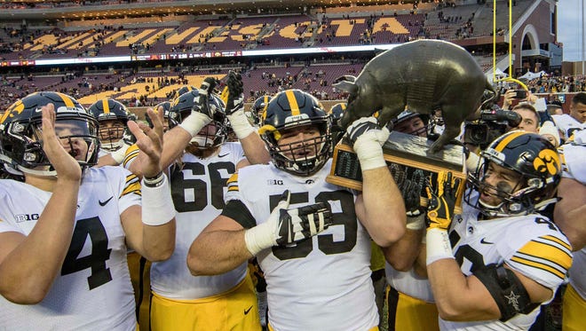 The Iowa Hawkeyes walk off the TCF Bank Stadium field with the Floyd of Rosedale trophy after beating Minnesota on Saturday, Oct. 6.
