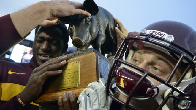 Minnesota's Bryan Klitzke, right, carries the Floyd of Rosedale trophy after defeating Iowa.