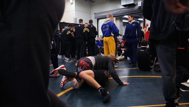 Wrestlers warm up before the championship round of the class 2A Iowa high school state wrestling tournament on Saturday, Feb. 17, 2018, in Wells Fargo Arena.