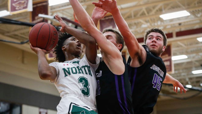 Des Moines North junior Tyreke Locure, left, drives in to the basket as he is defended by Johnston's Camden Vander Zwaag, center, and Nathan Newcomb, right, on Tuesday, Feb. 27, 2018, at Ankeny High School in Ankeny.