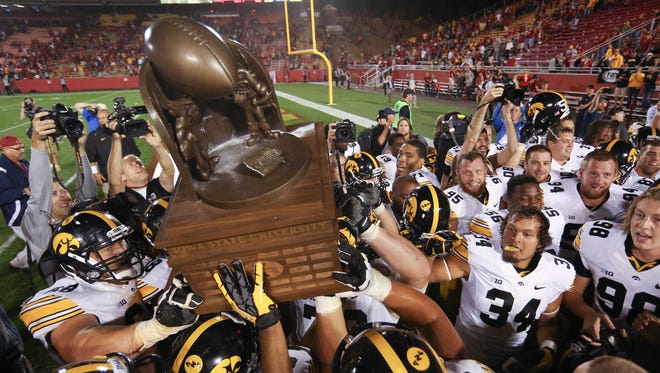 Iowa players hoist the Cy-Hawk trophy after beating Iowa State, 27-20, on Saturday, Sept. 15, 2013, at Jack Trice Stadium in Ames.