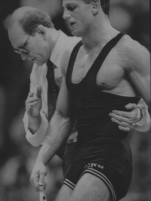 In this 1991 photo, Iowa wrestling coach Dan Gable helps Tom Ryan off the mat after a match.