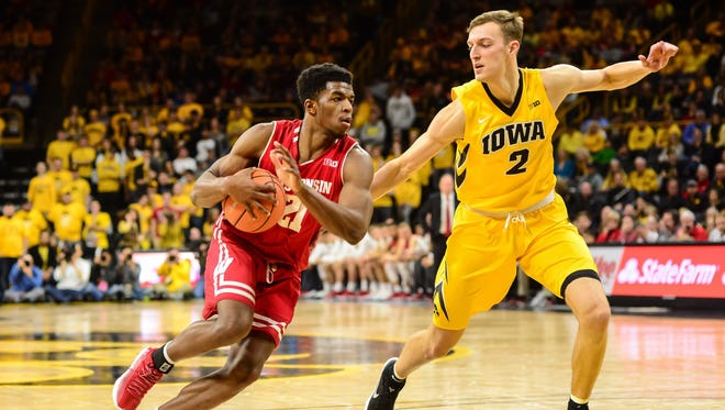 Badgers guard Khalil Iverson goes to the basket as Hawkeyes forward Jack Nunge defends.