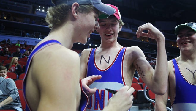 Reece Roberts, Reid Ehman and Joe Folkerts, students at Dike New Hartford High School write "Dilly Dilly" on their arms before the championship round of the class 2A Iowa high school state wrestling tournament on Saturday, Feb. 17, 2018, in Wells Fargo Arena.