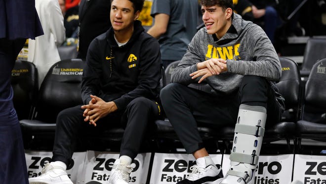 Injured Iowa players Cordell Pemsl, left, and Luka Garza sit on the bench during the second half of an NCAA college basketball game against Savannah State, Saturday, Dec. 22, 2018, in Iowa City, Iowa. (AP Photo/Charlie Neibergall)