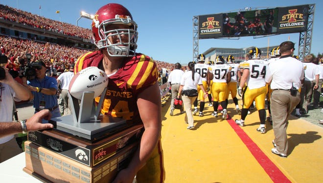 Iowa State's Tom Farniok grabs the Cy-Hawk trophy from the Iowa sideline after the Cyclones' 44-41 triple overtime win on Saturday, Sept. 10, 2011.