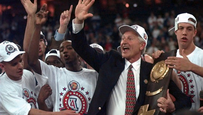 Arizona coach Lute Olson holds the trophy surrounded by celebrating players after beating Kentucky 84-79 in overtime to win the national championship March 31, 1997,  at the NCAA Final Four tournament in Indianapolis.