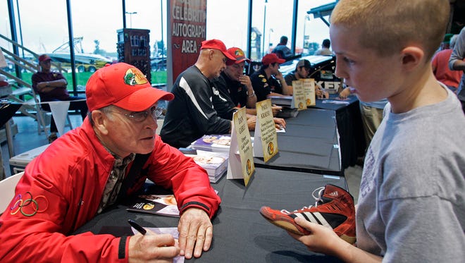 On Aug. 26, 2009, former Iowa wrestling coach Dan Gable, left, chatted with Reese Stahlbaum, 11 of Johnston, while signing autographs at the grand opening of Bass Pro Shops in Altoona.