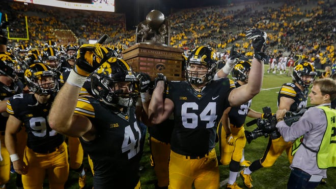 Iowa's Bo Bower, left, and Cole Croston carry the Cy-Hawk trophy off the field after a 42-3 win over Iowa State on Saturday, Sept. 10, 2016, at Kinnick Stadium in Iowa City.