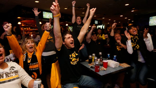 Hawkeye fans Cheryl Stacy of Waukee (from left), Rob Hutt of Waukee and Ashlee Sharp of Urbandale (right) cheer as Iowa completes a pass for a first down in Michigan State territory Saturday Dec. 5, 2015, as they watch the Big 10 championship game at The Front Row bar in Clive.