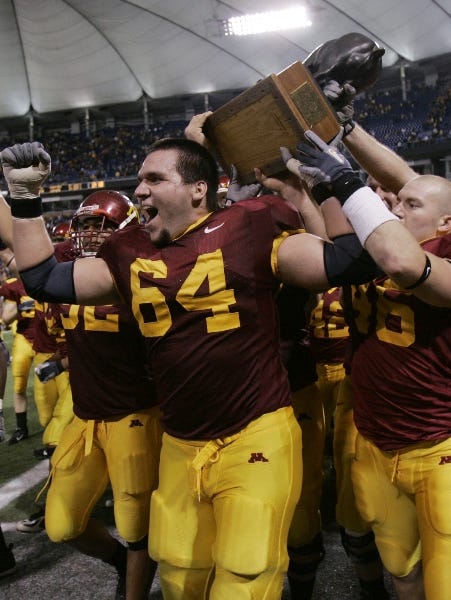 Minnesota's  Steve Shidell (64) and John Shevlin, right, lead the pack with the victor's spoils as they carry Floyd of Rosedale, a bronze pig, around the field after beating Iowa 34-24 in a football game Saturday, Nov. 18, 2006 in Minneapolis.
