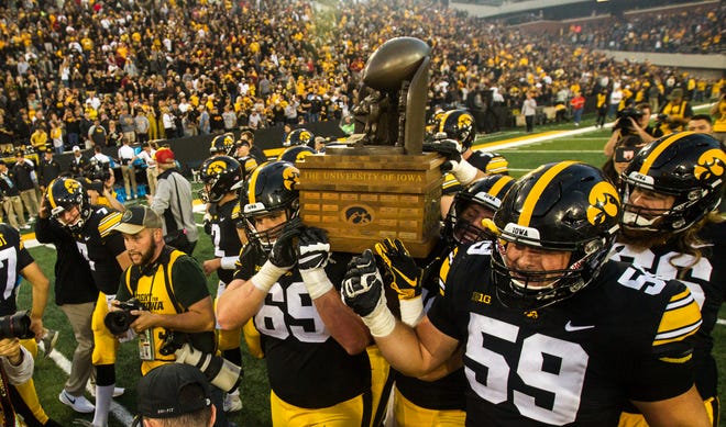 From 2018: Iowa offensive linemen Keegan Render (69) and Ross Reynolds (59) celebrate their 13-3 win over Iowa State by claiming the Cy-Hawk trophy after the 2018 rivalry game Sept. 8, 2018, at Kinnick Stadium in Iowa City.