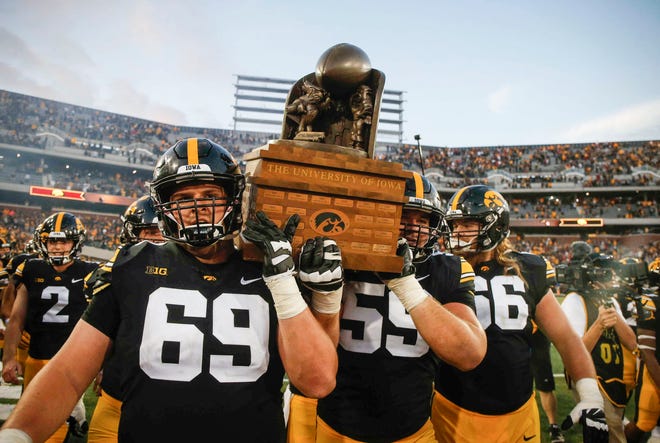Members of the Iowa Hawkeyes football team carry the CyHawk trophy off the field after a 13-3 win over Iowa State on Saturday, Sept. 8, 2018, at Kinnick Stadium in Iowa City.