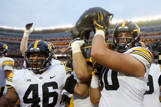 Iowa tight end Tommy Kujawa, left, and Iowa defensive end Sam Brincks celebrate their 48-31 win against Minnesota by carrying the Floyd of Rosedale rivalry trophy across the field after an NCAA college football game Saturday, Oct. 6, 2018, in Minneapolis. (AP Photo/Stacy Bengs)