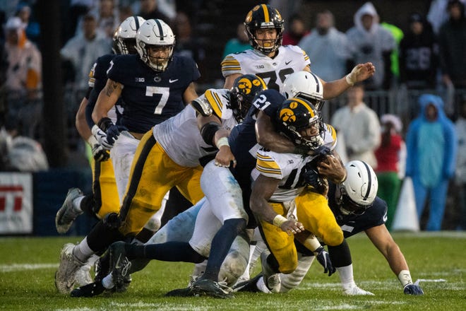 Mekhi Sargent #10 of the Iowa Hawkeyes is tackled by Amani Oruwariye #21 of the Penn State Nittany Lions and Antonio Shelton #55 of the Penn State Nittany Lions during a game at Beaver Stadium on Saturday, October 27, 2018, in State College, Pennsylvania.