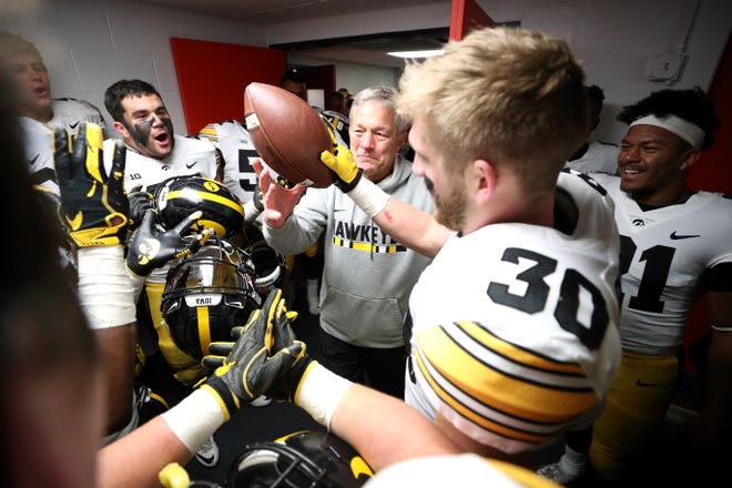 Iowa fifth-year senior Jake Gervase (30) gave Kirk Ferentz a game ball on behalf of the team following the coach's 150th career win at Iowa. Also pictured: Jack Hockaday, left, and Ivory Kelly-Martin, right.
