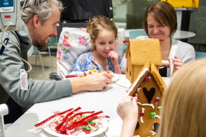 Ava Kruse (far right) places candy on a gingerbread hosue while John, Wrenlie and Kristie Bixler decorate a house at an event on Tuesday, Dec. 18, 2018, at the Stead Family Children's Hospital in Iowa City.