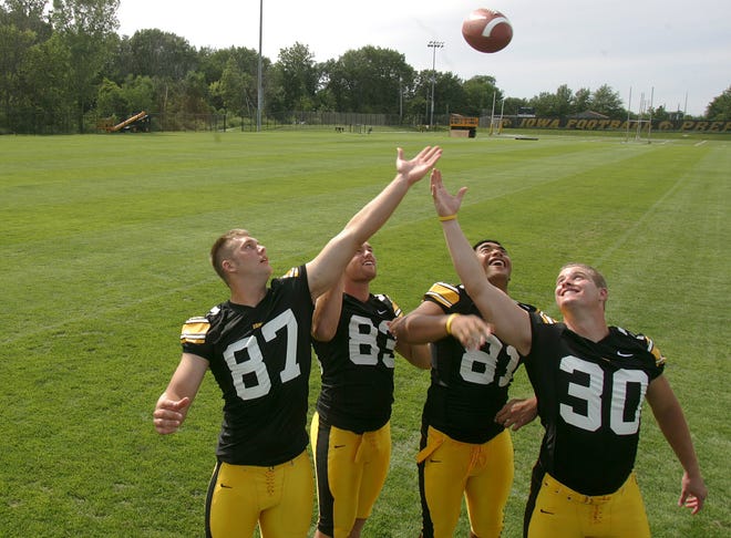 Iowa tight ends Scott Chandler, Brandon Myers, Tony Moeaki, and Ryan Majerus reach for the ball for a photo at Iowa football media day on Aug. 7, 2004.