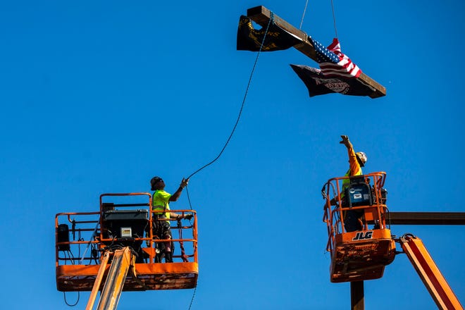 Workers help guide the final steel beam into the structure during a ceremony as construction continues, Wednesday, Aug. 28, 2019, at the Xtream Arena and Fieldhouse in Coralville, Iowa.