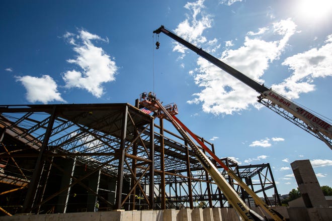 Workers help guide the final steel beam into the structure during a ceremony as construction continues, Wednesday, Aug. 28, 2019, at the Xtream Arena and Fieldhouse in Coralville, Iowa.