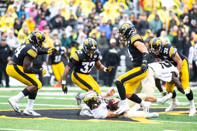 Purdue quarterback Jack Plummer (13) slides to avoid tackles from Iowa linebacker Djimon Colbert (32) and Iowa defensive back Dane Belton (4) during a NCAA Big Ten Conference football game between the Iowa Hawkeyes and Purdue, Saturday, Oct., 19, 2019, at Kinnick Stadium in Iowa City, Iowa.