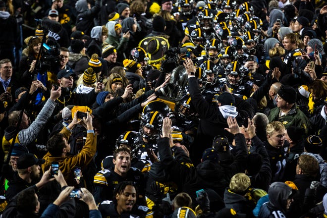 Iowa Hawkeyes players carry the Floyd of Rosedale trophy through a swarm of fans after a NCAA Big Ten Conference football game, Saturday, Nov., 16, 2019, at Kinnick Stadium in Iowa City, Iowa. The Hawkeyes defeated Minnesota, 23-19.
