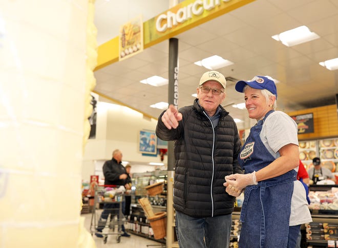 Dan Gable and Sarah "Cheese Lady" Kaufmann review the tribute together during a meet and greet with Iowa wrestling legend Dan Gable and a 3,000-pound wheel of aged white cheddar cheese sculpture of him on Sunday, Nov. 17, 2019, at the Hy-Vee, 410 N. Ankeny Blvd., in Ankeny.