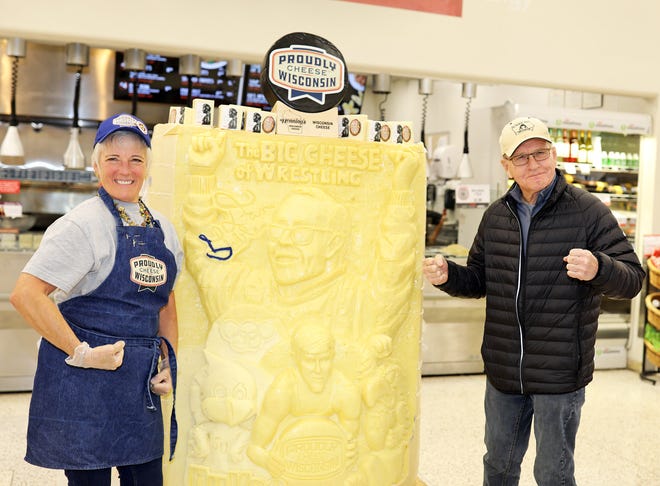 Dan Gable and Sarah "Cheese Lady" Kaufmann flex their muscles during a meet and greet with Iowa wrestling legend Dan Gable and a 3,000-pound wheel of aged white cheddar cheese sculpture of him on Sunday, Nov. 17, 2019, at the Hy-Vee, 410 N. Ankeny Blvd., in Ankeny.