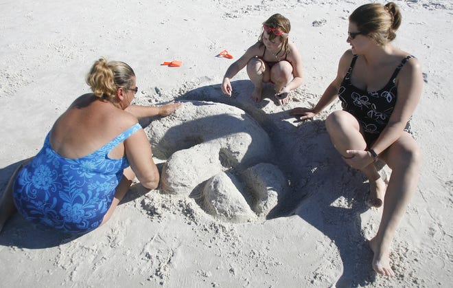 Donna Sharp, of Eldridge, left, works on a sand sculpture of a tigerhawk with her daughter Andi Slack, of Waterloo, right, and her grandaughter Vivian Slack, 6, during the Outback Bowl "Beach Day" at Clearwater Beach, Tuesday, Dec. 30, 2008, in Clearwater, Fla.