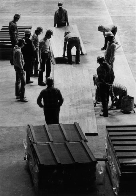A crew from the Athletic Department pieces together the wood floor, Dec. 28, 1982, at Carver-Hawkeye Arena in Iowa City, Iowa.