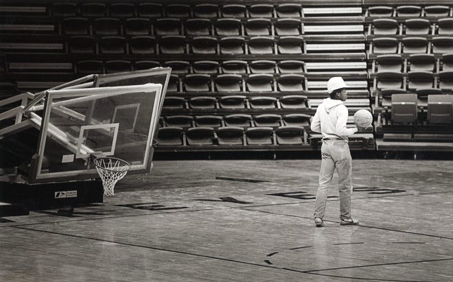 An undated photo of a construction worker playing with a basketball, at Carver-Hawkeye Arena in Iowa City, Iowa.
