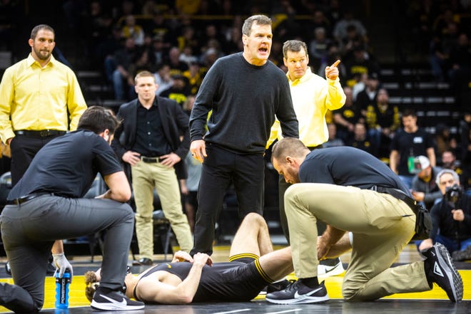 Iowa associate head coach Terry Brands calls out to an official while trainers check on Austin DeSanto during his match at 133 pounds during a NCAA Big Ten Conference wrestling dual, Friday, Jan. 31, 2020, at Carver-Hawkeye Arena in Iowa City, Iowa.