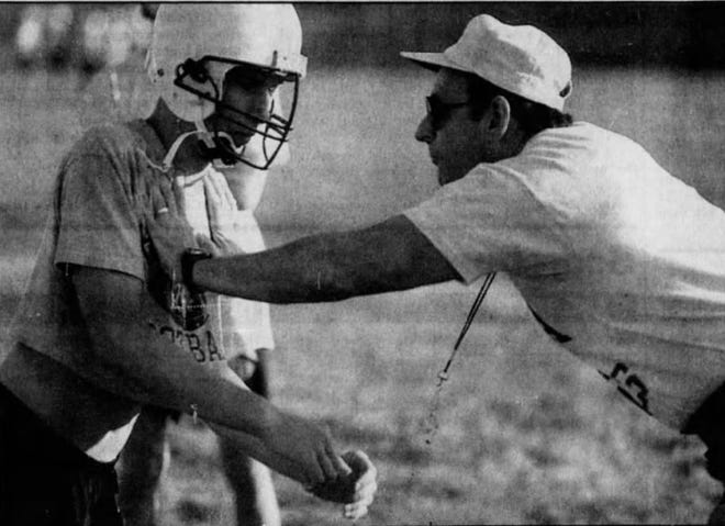 Iowa City Regina coach John DeMarco demonstrates a drill with Brett Hoffman during the first day of Regina football practice in August, 1992.