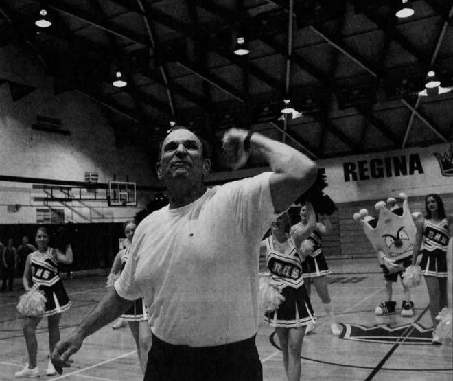 Coach John DeMarco leads Regina students through a rousing "gold fight, blue fight" cheer.