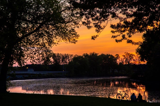 A couple sits along the Iowa River as the sun sets during the novel coronavirus pandemic, Tuesday, May 12, 2020, at CRANDIC Park in Iowa City, Iowa.