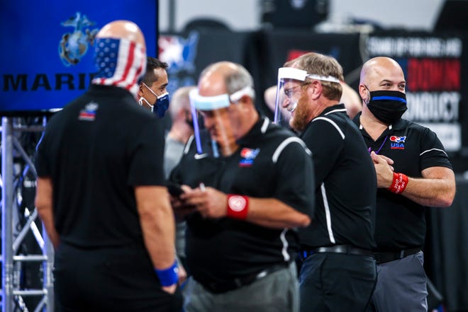 Officials wearing face masks and shields huddle up between sessions during the USA Wrestling Senior National Championships, Friday, Oct. 9, 2020, at the Xtream Arena in Coralville, Iowa.