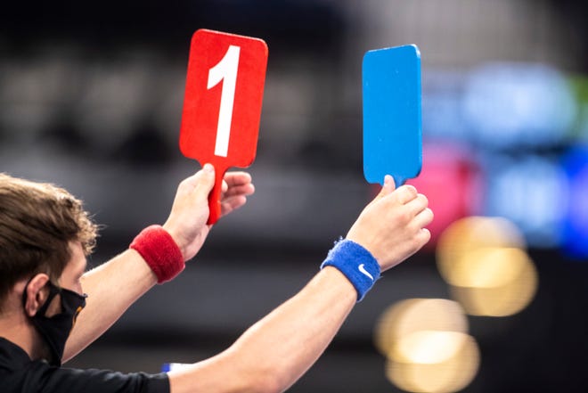 An official wearing a face mask holds up cards updating score during the USA Wrestling Senior National Championships, Friday, Oct. 9, 2020, at the Xtream Arena in Coralville, Iowa.