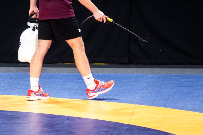 A person disinfects mats between sessions during the USA Wrestling Senior National Championships, Friday, Oct. 9, 2020, at the Xtream Arena in Coralville, Iowa.
