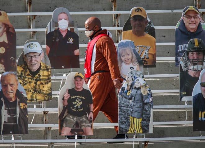A member of television media walks among cardboard cutouts prior to Iowa's kickoff against Northwestern at Kinnick Stadium in Iowa City on Saturday, Oct. 31, 2020.