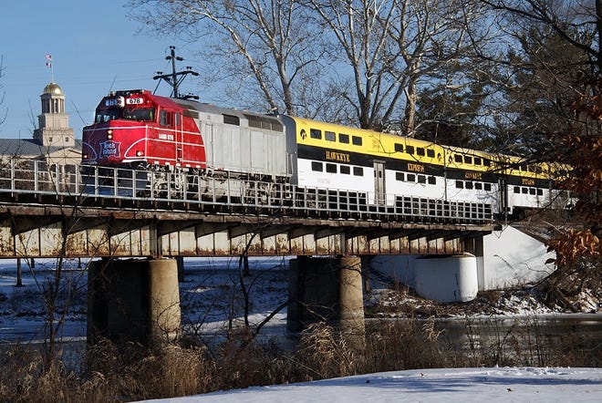 This unique photo shows the Hawkeye Express on special event trip with the University of Iowa Old Capitol building in the background, operating on the CRANDIC rail line. The Hawkeye Express ceased operation last year.