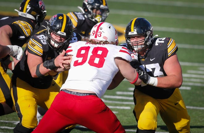 Iowa center Tyler Linderbaum, right, and left guard Cody Ince hold Nebraska's Casey Rogers back in the second quarter at Kinnick Stadium in Iowa City on Friday, Nov. 27, 2020.