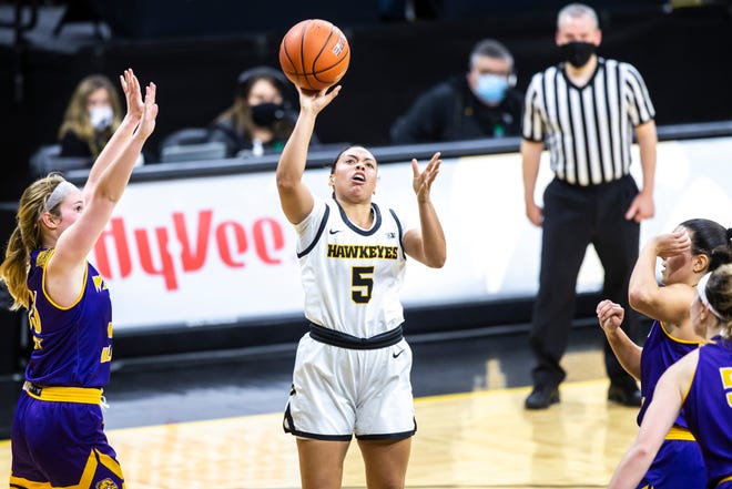 Iowa guard Alexis Sevillian (5) makes a basket as Western Illinois guards Anna Deets, left, and Carla Flores defend during a NCAA non-conference women's basketball game, Tuesday, Dec. 22, 2020, at Carver-Hawkeye Arena in Iowa City, Iowa.