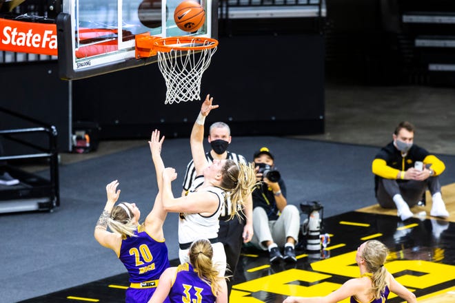 Iowa center Monika Czinano (25) makes a basket as Western Illinois' Maddie Mock (20) and Anna Deets (33) defend during a NCAA non-conference women's basketball game, Tuesday, Dec. 22, 2020, at Carver-Hawkeye Arena in Iowa City, Iowa.